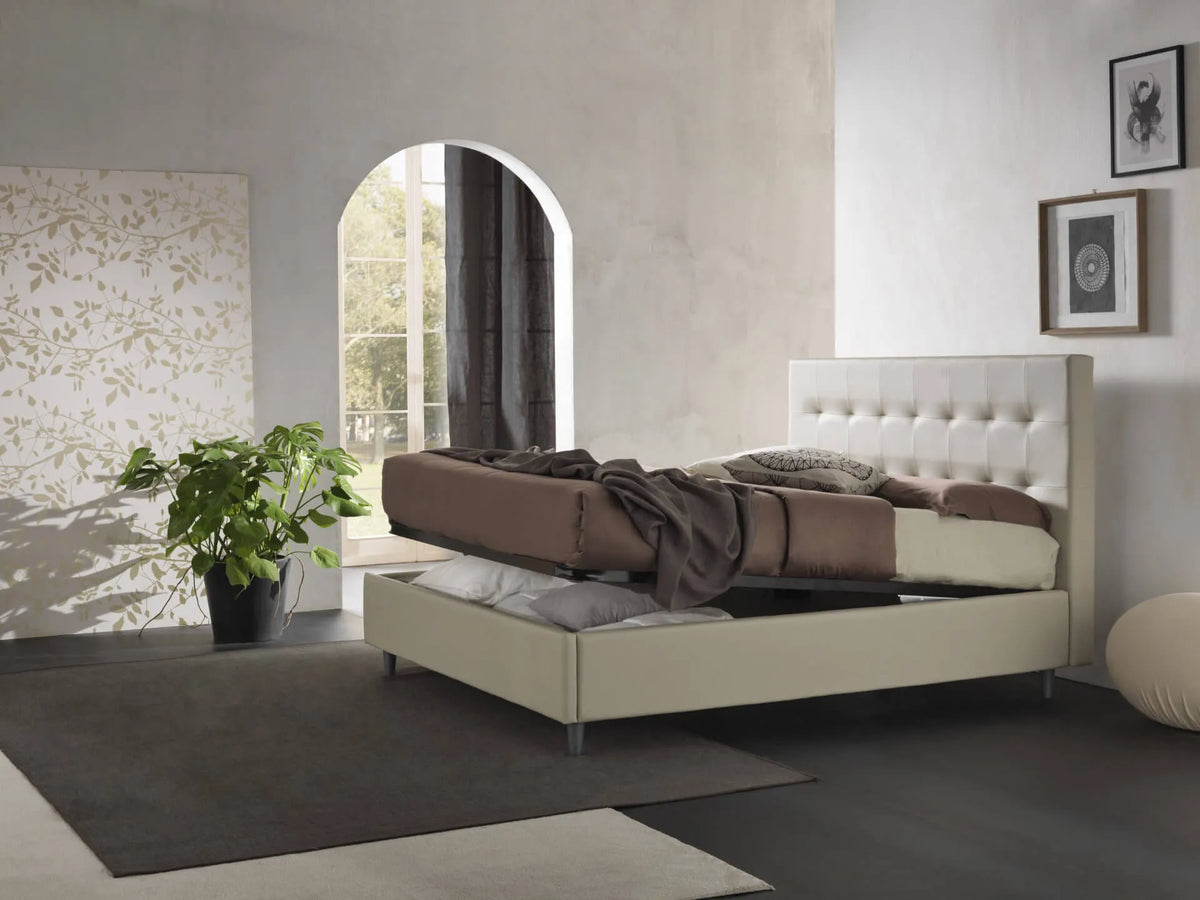 Letto New York imbottito con contenitore salvaspazio, testata trapuntata e piedini alti. Rete a doghe, materiali resistenti e design moderno.