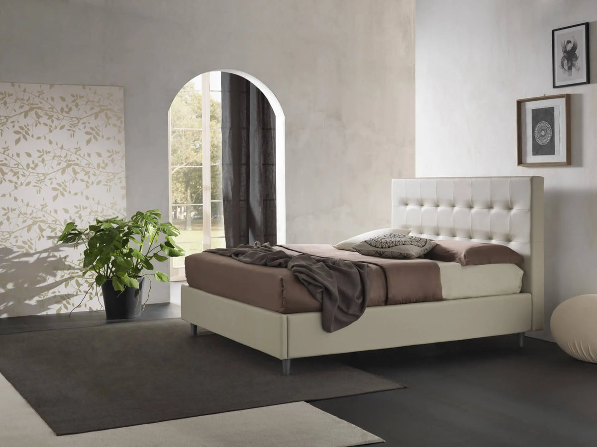 Letto New York imbottito con contenitore salvaspazio, testata trapuntata e piedini alti. Rete a doghe, materiali resistenti e design moderno.