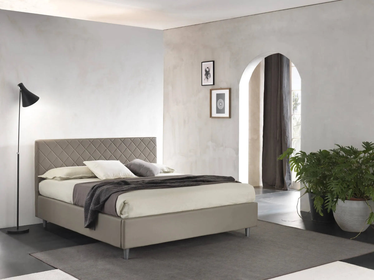 Letto matrimoniale Rio con contenitore, rivestimento in ecopelle e testata imbottita trapuntata a rombi. Design moderno, elegante e salvaspazio.

